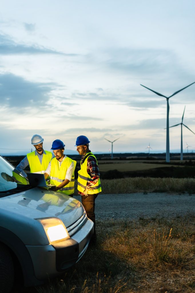 Engineers teamwork discussing renewable energy project at wind turbine farm